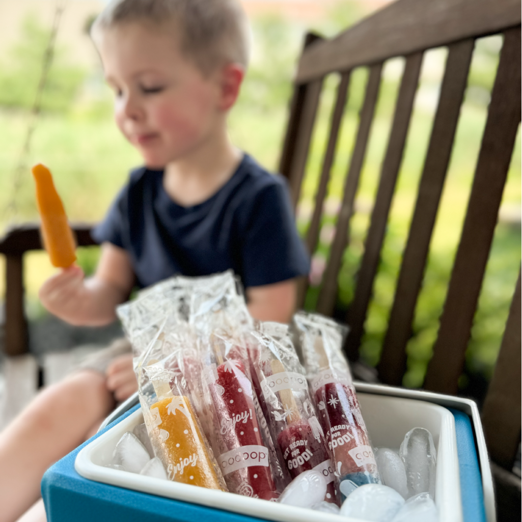 Boy eating GoodPop Juinior Pops with full cooler near by